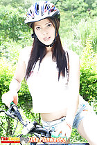 Riding bike long hair under her helmet wearing denim shorts